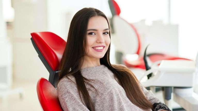 woman sitting in a red dental chair