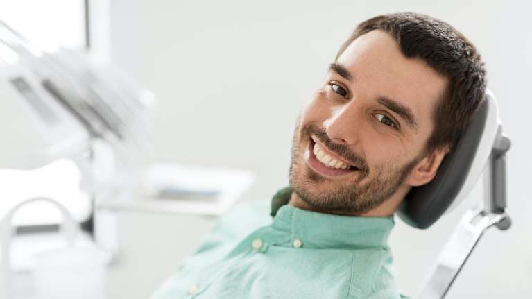 man with green shirt sitting in adental chair